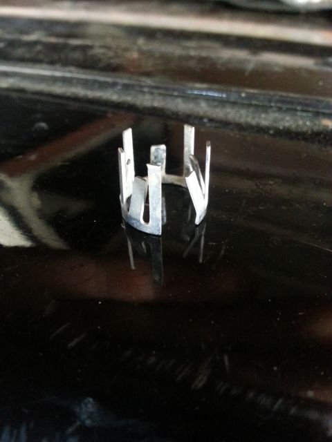 1978 Ford Bronco - A close-up, eye-level shot shows a small, silver metal clip with multiple prongs against a dark, reflective surface. The clip appears to be…