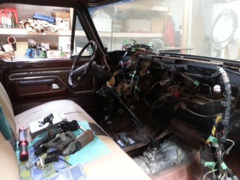 1978 Ford Bronco - Disassembled truck cab showing gutted dashboard, exposed wiring and steering parts laid on the bench seat.