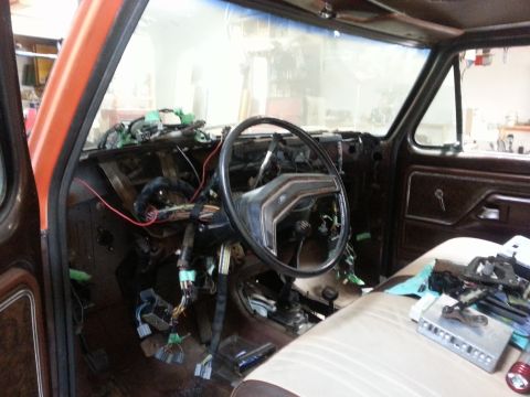 1978 Ford Bronco - The interior of a classic Ford truck or SUV is shown with the dashboard disassembled, revealing extensive wiring and components. The steeri…