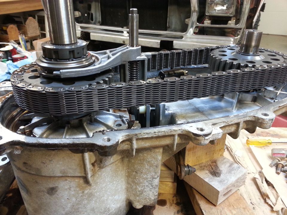 Close-up of a vehicle transfer case with chain and gears exposed.