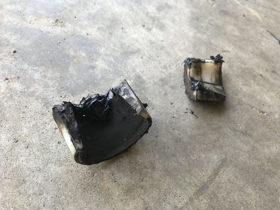 Two pieces of burnt, melted material on concrete
