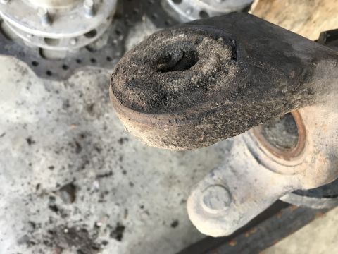 1989 Ford Bronco - A close-up view of a heavily soiled and worn metal suspension component, likely from a vehicle's undercarriage. The part shows significant…