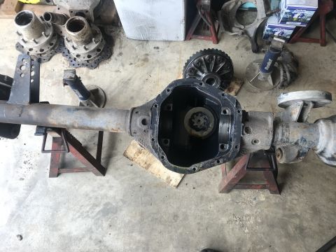 1989 Ford Bronco - A disassembled Ford Bronco rear axle assembly is shown resting on jack stands in a garage. The differential cover is removed, revealing the…