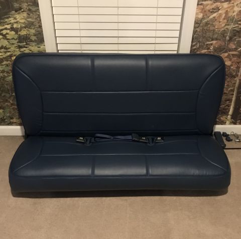 1995 Ford Bronco - A dark blue bench seat with seatbelts is shown against a backdrop of blinds and a nature-themed wallpaper. The seat appears to be from a ve…