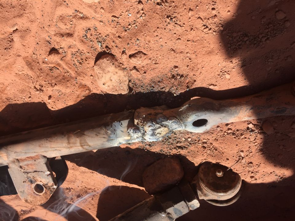 Welded metal rod on dirt with smoke rising.