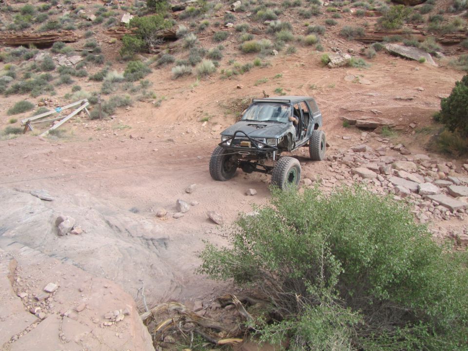 Modified dark SUV on a rocky off-road trail.