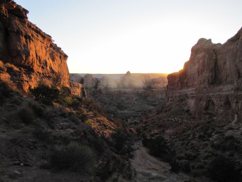 1984 Ford Bronco - A wide canyon landscape at sunset with the sun casting a warm glow on the rock formations.