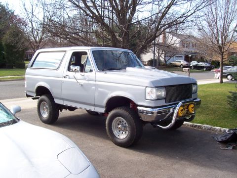 1990 Ford Bronco - This silver Ford Bronco SUV, likely from the early 1990s, is shown from a three-quarter front angle.