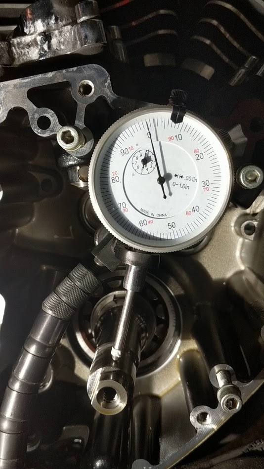 Dial indicator measuring an engine part, showing a reading slightly below zero.