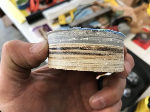 1923 Ford Model T - A hand holds a layered circular object that appears to be made of wood and some sort of plastic or composite material. The object has visib…