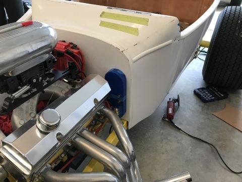 1923 Ford Model T - A close-up view of a chrome engine with a red marker on the air cleaner housing, mounted in a white fiberglass body. Tools and a large tire…