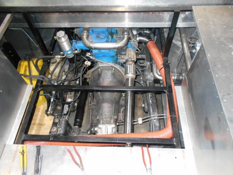 1992 Ford Bronco - A view of the engine compartment of a vehicle, showing a blue engine, transmission, and various hoses and mechanical components. The engine…