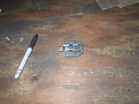 1992 Ford Bronco - A metal latch mechanism is shown on a wooden surface, next to a black marker and two nuts. The latch appears to be part of a toolbox or cas…