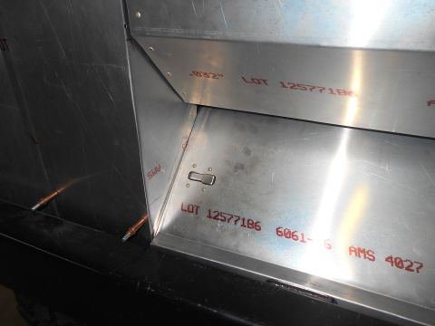 1992 Ford Bronco - Close-up view of aluminum sheet metal construction with red stenciled markings. Visible text includes "LOT 125771B6 6061-6 AMS 4027" and a…