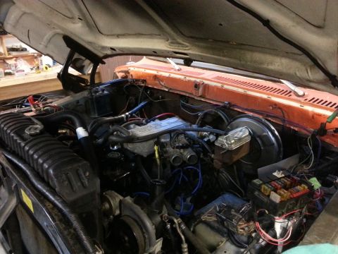 1978 Ford Bronco - The open hood of a classic Ford truck reveals a detailed view of the engine bay, showcasing the engine, radiator, battery, and various hose…