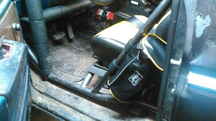 1978 Ford Bronco - Interior view of a modified vehicle, likely a Ford Bronco, showing a roll cage, racing seat with yellow accents, and a black storage bag at…
