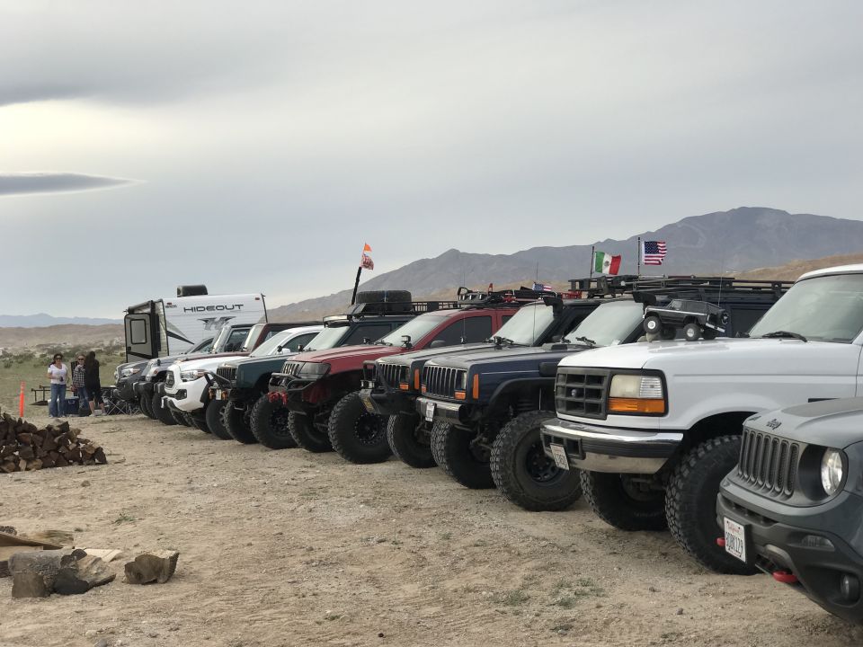 Several off-road vehicles parked in a line, with a white Ford Bronco in the foreground.