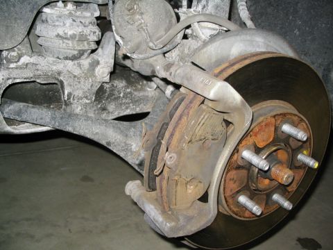 1996 Mercury Sable - Close-up view of a vehicle's rear brake caliper and rotor, showing signs of rust and wear.