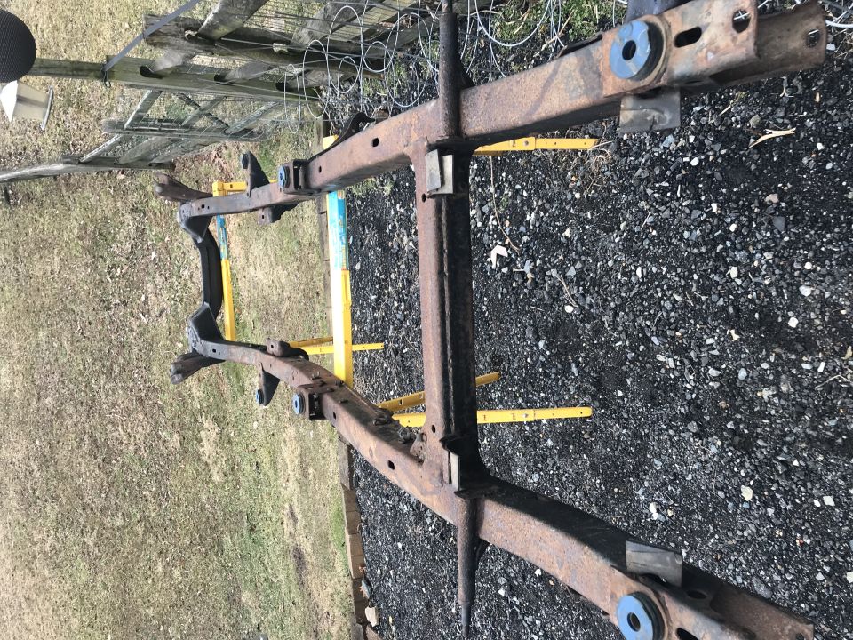 Rusted vehicle frame on yellow jack stands outdoors