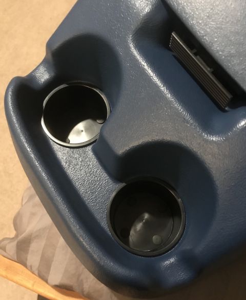1995 Ford Bronco - A close-up view of a blue plastic center console with two cup holders and a metal slide lever. The cup holders appear to be for a vehicle i…
