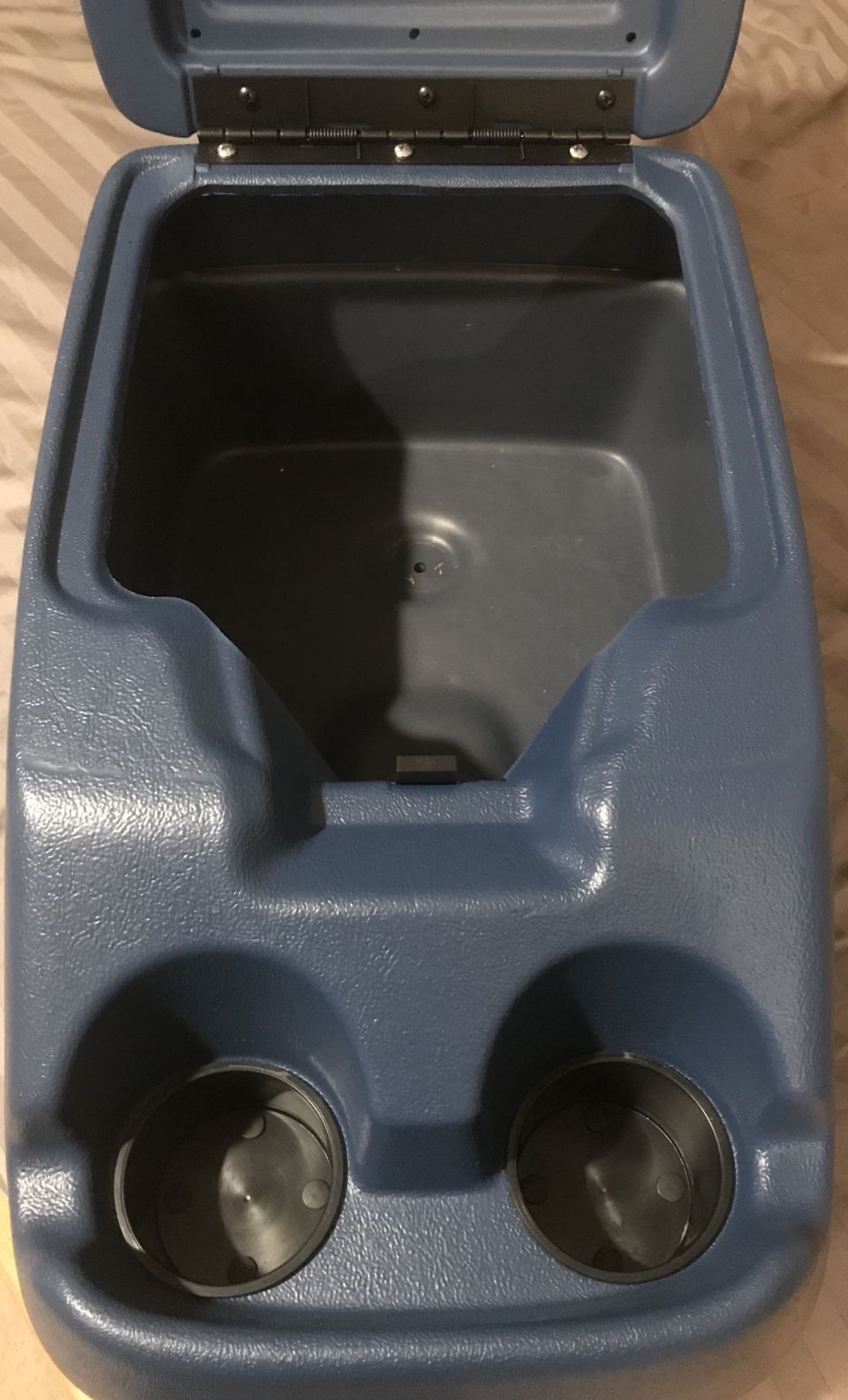 Blue plastic center console with open lid and two cup holders.