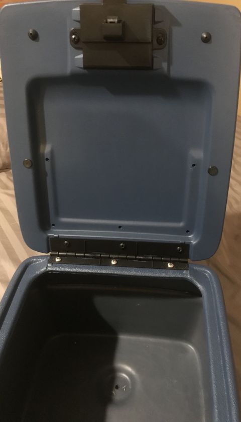 1995 Ford Bronco - The interior of an open blue center console box is shown, with visible hinges and a latch mechanism on the lid.