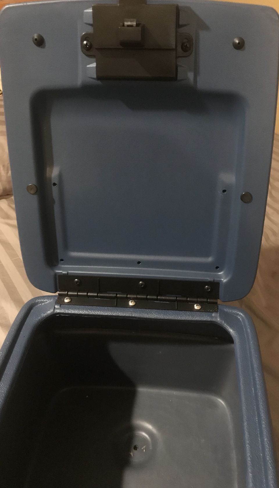 Open blue center console interior with hinges and latch