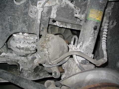 1996 Mercury Sable - Close-up of dusty rear brake caliper and suspension parts, with a Motorcraft sticker on the shock.