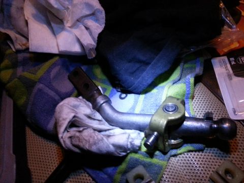 1978 Ford Bronco - A close-up view of a metal shift lever assembly with a brass-colored bracket, resting on a blue and green patterned cloth. A dirty white ra…