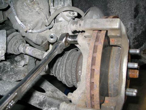 1996 Mercury Sable - Mechanic uses a socket wrench to remove a brake caliper during a brake upgrade procedure.