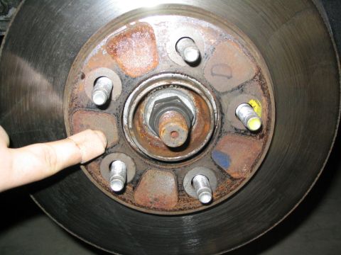 1996 Mercury Sable - A finger points to the lug nut area of a rusty brake rotor and hub assembly, with a SuperMotors.net watermark visible.