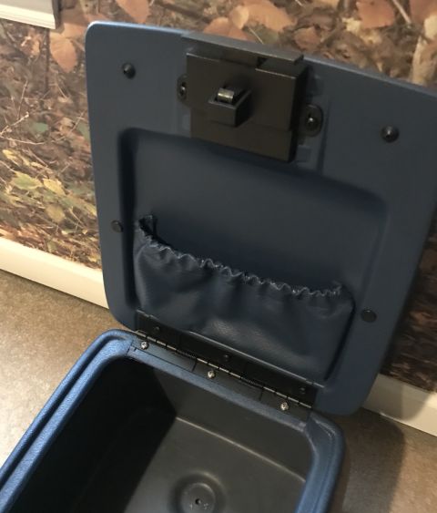 1995 Ford Bronco - The open blue interior of a vehicle's center console storage compartment is shown. A black latch mechanism is visible on the underside of t…