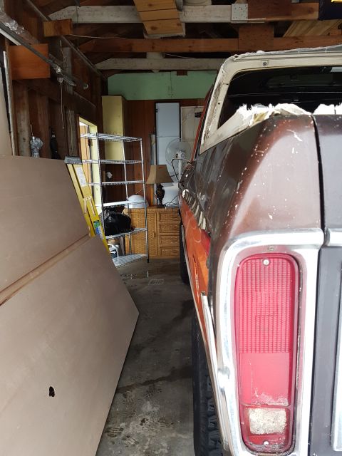 1978 Ford Bronco - The rear passenger side of a brown 1978 Ford Bronco is visible in a garage, parked next to large wooden boards. The vehicle's taillight and…