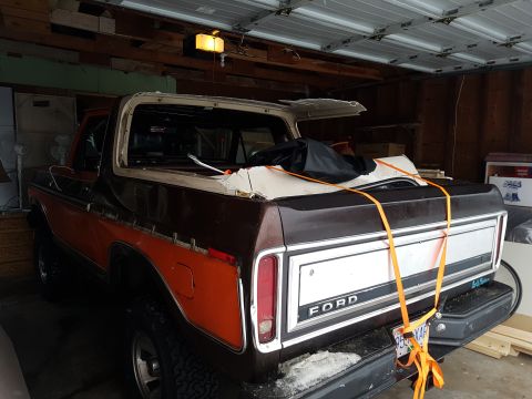 1978 Ford Bronco - The rear passenger side of a brown and orange 1978 Ford Bronco is shown in a garage. The removable roof is detached and resting on the bed,…