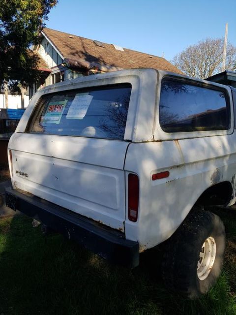 1978 Ford Bronco - The rear passenger side of a white Ford Bronco is shown parked on grass with a house in the background. Two 'For Sale' signs are visible on…