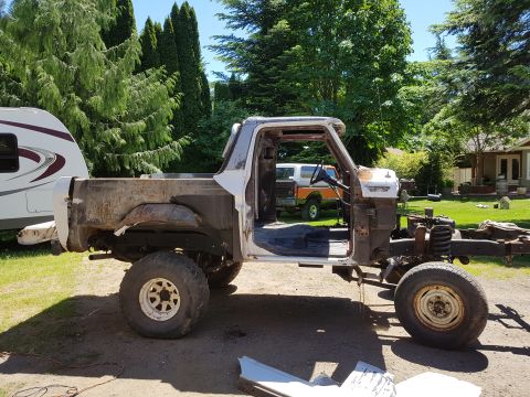 1978 Ford Bronco - A partially disassembled 1978 Ford Bronco sits in a grassy yard on a sunny day. The truck is missing its hood, fenders, and doors, revealin…