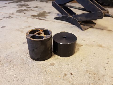1978 Ford Bronco - Two suspension lift blocks are shown on a concrete surface. The block on the left is rusted and has cutouts, while the block on the right i…