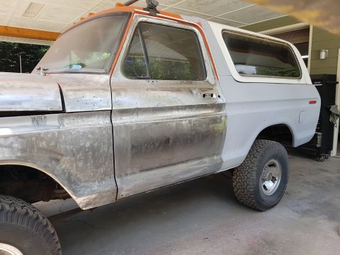 1978 Ford Bronco - A side view of a classic Ford Bronco undergoing restoration. The vehicle's body is in various stages of repair, with some sections showing…