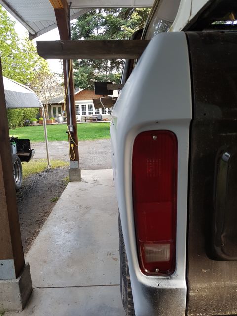 1978 Ford Bronco - The rear passenger side of a classic Ford Bronco is shown, prepped for paint with primer on the fender and rear quarter panel. The red tail…