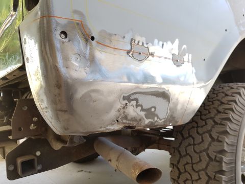 1978 Ford Bronco - The rear quarter panel of a vehicle is shown undergoing bodywork. The metal has been stripped and prepped for repair, with visible rust spo…