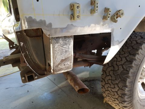 1978 Ford Bronco - A close-up view of the rear quarter panel of a vehicle undergoing repair, showing metalwork, suspension components, and a tire.