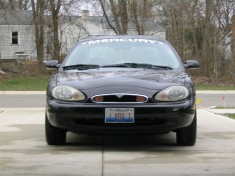 1996 Mercury Sable - The car's front end is visible, parked on a concrete driveway with houses and trees in the background.