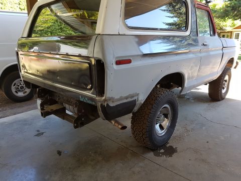 1978 Ford Bronco - The rear driver's side of a white 1978 Ford Bronco undergoing restoration is shown. The vehicle has primer gray body panels and exposed met…