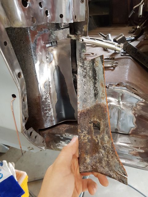 1978 Ford Bronco - A person holds a rusted piece of metal trim that has been removed from a vehicle. The surrounding area shows exposed metal, likely from a c…