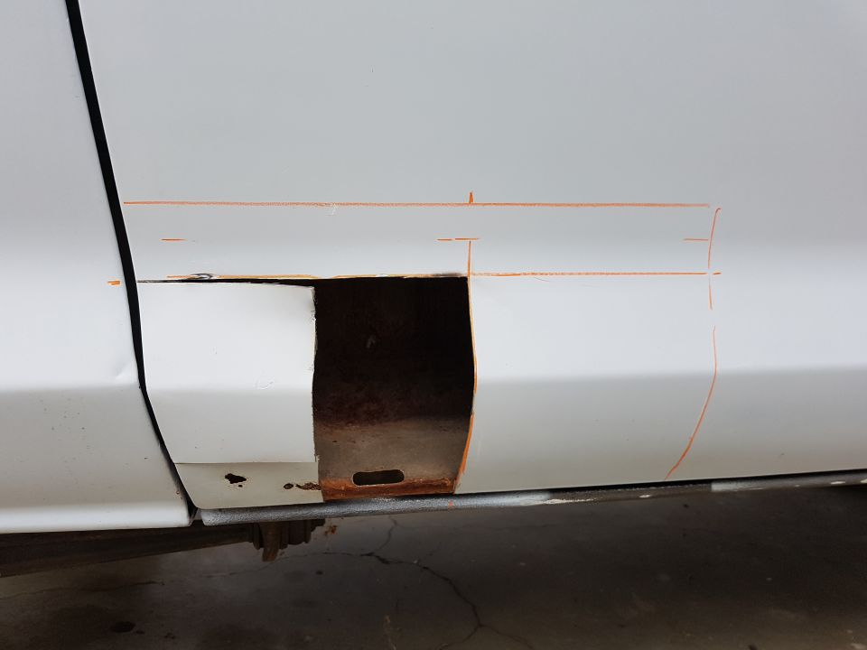 White vehicle door with a rusted cutout and orange marking lines.