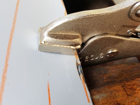 1978 Ford Bronco - A close-up shot shows a metal clamp holding two pieces of white metal together, with orange markings visible on the left piece. The clamp h…