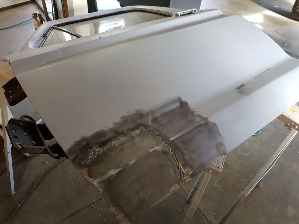 Vehicle door with metal repair and welding, supported by sawhorses.
