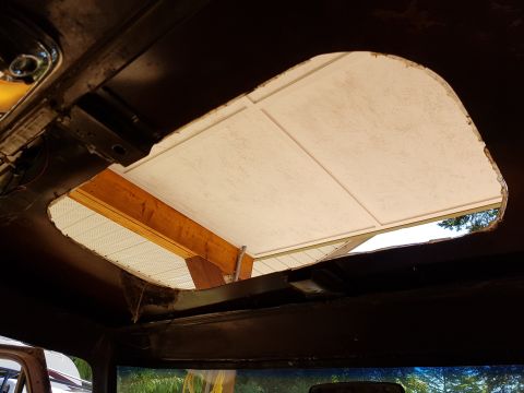 1978 Ford Bronco - View from inside a vehicle looking up at a large opening in the roof, revealing wooden beams and a white ceiling structure above. The openi…