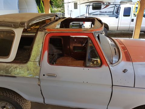 1978 Ford Bronco - The driver's side of a classic Ford Bronco is shown undergoing restoration. The roof has been removed, and the body is prepped with primer…
