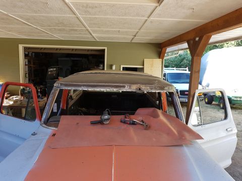 1978 Ford Bronco - The roof of a vintage SUV is being worked on, with tools like a grinder and drill laid out on a piece of sheet metal covering the hood. The…